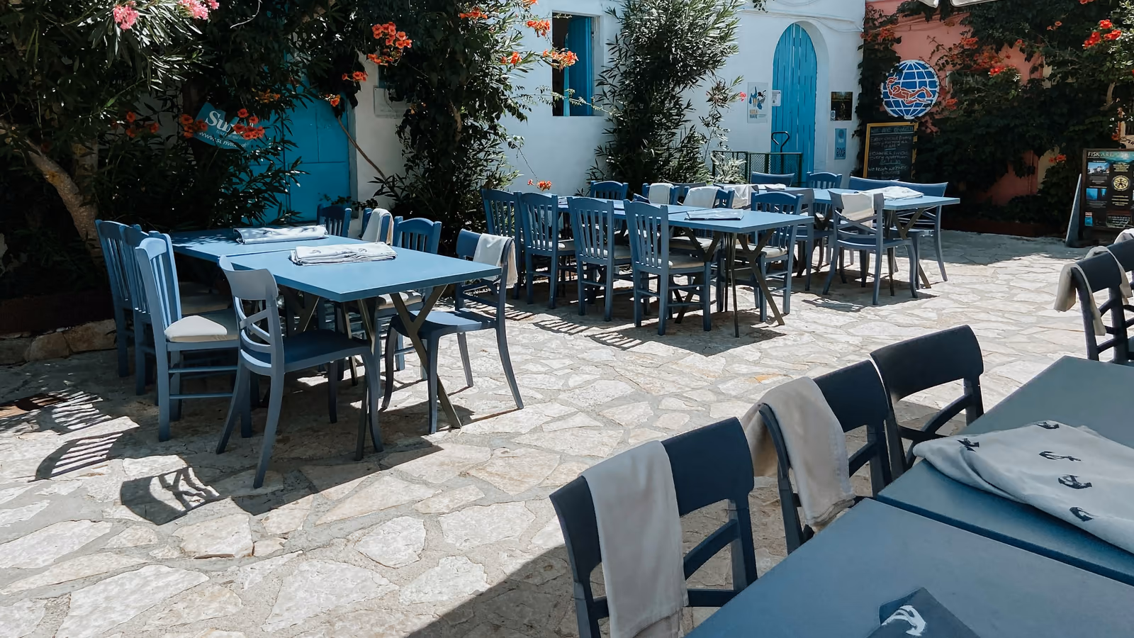 Τραπέζια με λευκά τραπεζομάντηλα κάτω από κληματαριά, το σούρουπο